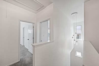 Hallway with attic access and carpet flooring
