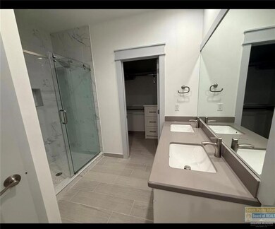 Bathroom with a marble finish shower, double vanity, and a spacious closet
