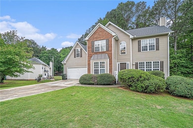 View of front facade featuring a chimney, driveway, a front yard, and an attached garage