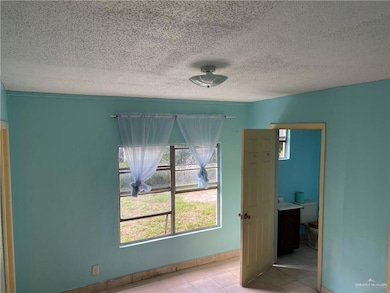 Unfurnished bedroom with light tile patterned floors and a textured ceiling