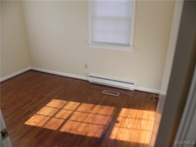 Empty room with dark wood-type flooring and a baseboard radiator