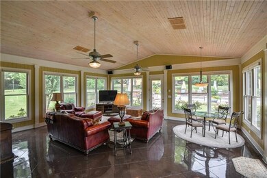 WOW!  The Living room is a  huge Florida Room.  Surrounded by windows, this room is sunny and bright with a panoramic view of the in-ground pool outside.  The floor is scored concrete and the vaulted ceiling is paneled and enhanced by 2 ceiling fans.