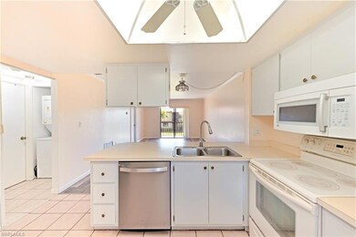 Kitchen featuring white appliances, a sink, light countertops, a peninsula, and a ceiling fan