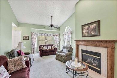 Carpeted living room with ceiling fan, a textured ceiling, lofted ceiling, and a fireplace