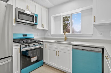 Kitchen with stainless steel appliances, white cabinets, and light wood-type flooring