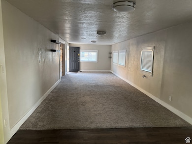 Unfurnished room with carpet, a textured ceiling, wood finished floors, and a textured wall