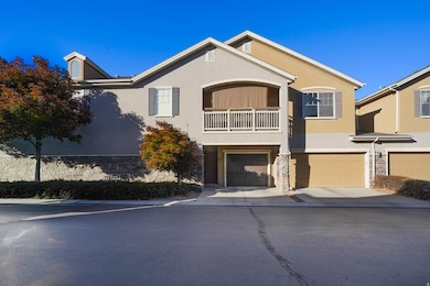 View of front of property with a balcony, stucco siding, a garage, driveway, and stone siding