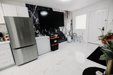 Kitchen featuring freestanding refrigerator, white cabinetry, light countertops, light marble finish flooring, and a textured ceiling