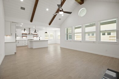 Great room features soaring vaulted ceiling with stained beams & shiplap detail