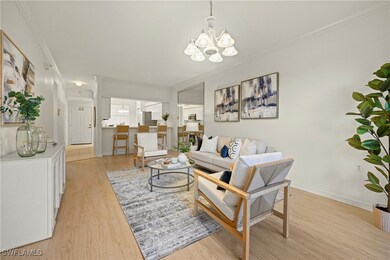 Living room with a chandelier, ornamental molding, and light wood-style flooring