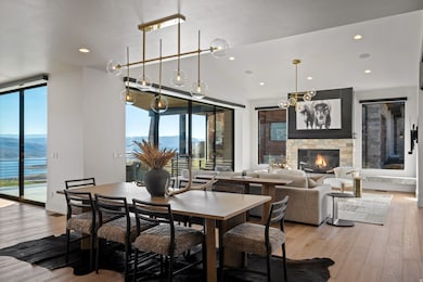 Dining room with light wood-type flooring, recessed lighting, a stone fireplace, and a water and mountain view