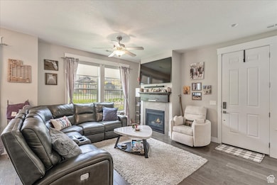 Living room featuring wood finished floors, a tile fireplace, a textured ceiling, and ceiling fan