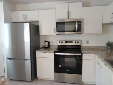 Kitchen with white cabinetry, appliances with stai