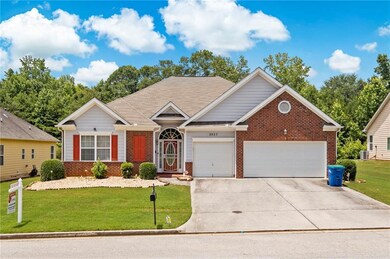 Single story home featuring an attached garage, a front yard, driveway, and brick siding