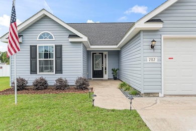 View of front of property with an attached garage, roof with shingles, and a front yard