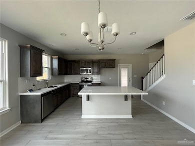 Kitchen featuring tasteful backsplash, stainless steel appliances, a center island, light wood-type flooring, and a chandelier