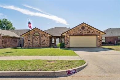 View of front of home with a garage, concrete driveway, brick siding, and a front lawn