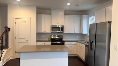 Kitchen with stainless steel appliances, white cabinets, tasteful backsplash, and recessed lighting