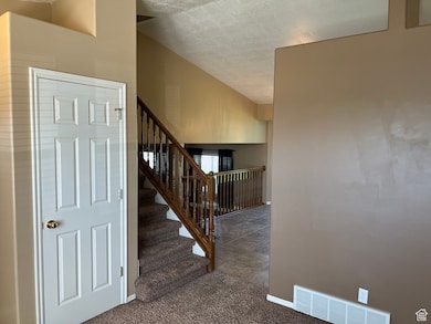 Stairs with carpet flooring, a textured ceiling, and vaulted ceiling