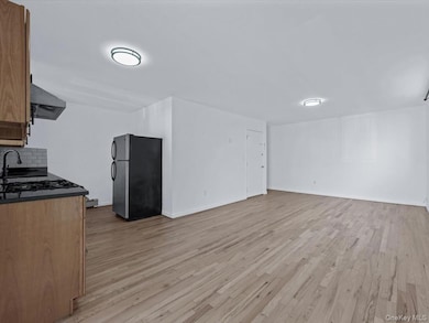 Kitchen featuring freestanding refrigerator, light wood-style floors, brown cabinets, and open floor plan