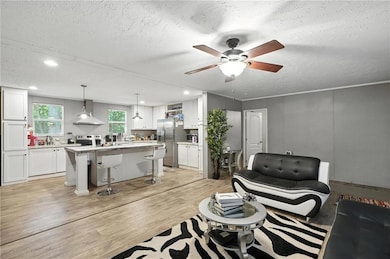 Living room with a textured ceiling, a ceiling fan, light wood-style floors, and recessed lighting