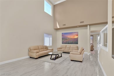 Living room featuring plenty of natural light, light marble finish flooring, crown molding, and a high ceiling