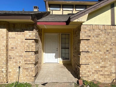 Entrance to property with a shingled roof and bric