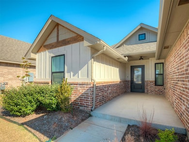 View of exterior entry featuring roof with shingles, board and batten siding, and brick siding