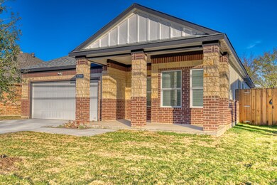 View of front of home with covered porch, brick siding, board and batten siding, an attached garage, and concrete driveway