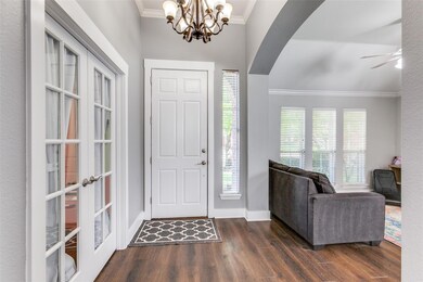 Foyer entrance featuring ceiling fan with notable chandelier, plenty of natural light, dark hardwood / wood-style floors, and crown molding