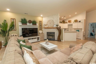 Living room with a fireplace, recessed lighting, light wood-style floors, and high vaulted ceiling