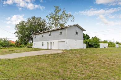 Back of house with driveway, an attached garage, a yard, and stucco siding