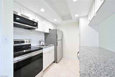 Kitchen featuring stainless steel appliances, backsplash, white cabinetry, light stone counters, and recessed lighting