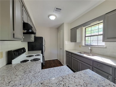Kitchen featuring gray cabinets, electric range, and light stone counters