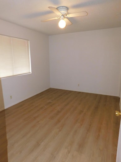 Spare room with light wood finished floors, ceiling fan, and a textured ceiling