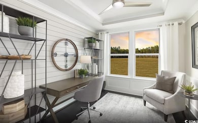 Office area with a tray ceiling, a ceiling fan, and wood finished floors