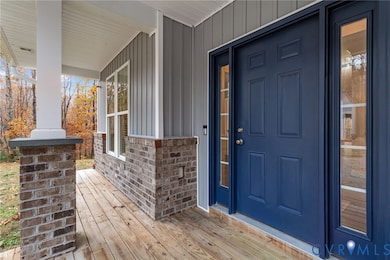 Property entrance featuring board and batten siding, brick siding, and covered porch