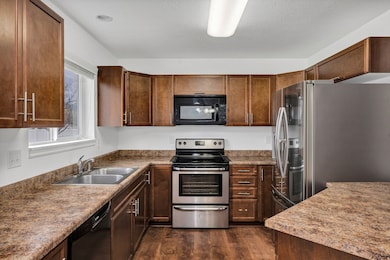 Kitchen with black appliances, dark wood-type flooring, and dark stone countertops