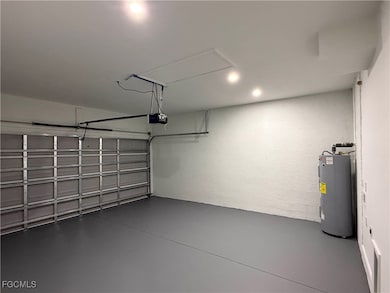 Garage with electric water heater, a textured wall, and a garage door opener