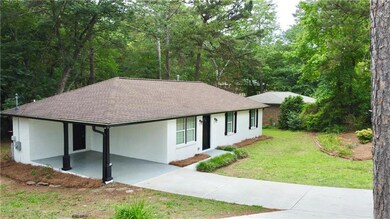 Ranch-style house featuring a shingled roof, driveway, an attached carport, and a front yard