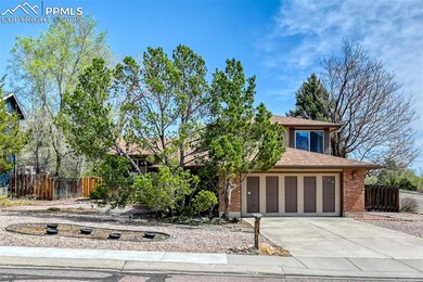 View of front of home featuring roof with shingles, brick siding, driveway, and fence