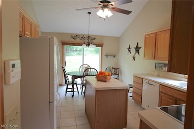 Kitchen with lofted ceiling, decorative light fixtures, white appliances, and a kitchen island