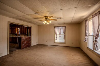 Unfurnished living room featuring carpet flooring, a paneled ceiling, and a ceiling fan