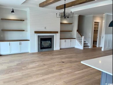 Unfurnished living room featuring a chandelier, light wood-style flooring, stairway, ornamental molding, and beamed ceiling