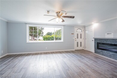 Unfurnished living room featuring ceiling fan, a fireplace, hardwood / wood-style flooring, and ornamental molding