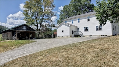 Front of property featuring a lawn, an outbuilding, and driveway