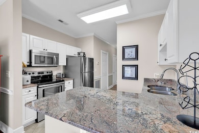 Kitchen featuring a peninsula, a sink, appliances 