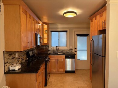 Kitchen with stainless steel appliances, a sink, tasteful backsplash, and brown cabinetry