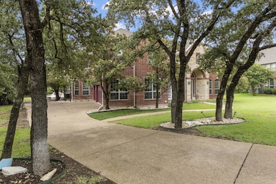 View of property hidden behind natural elements featuring driveway, brick siding, a front yard, and a garage