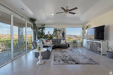 Living area with a raised ceiling, ceiling fan, tile patterned flooring, and recessed lighting